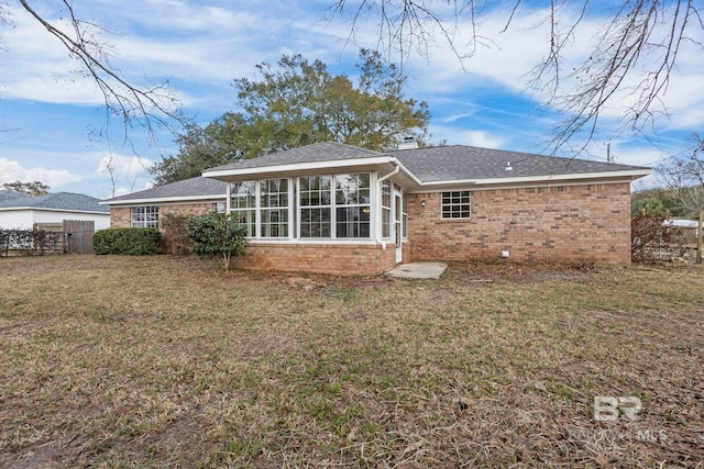 rear view of house with a sunroom and a lawn