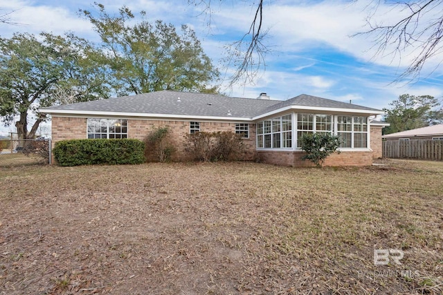 rear view of house featuring a lawn and a sunroom