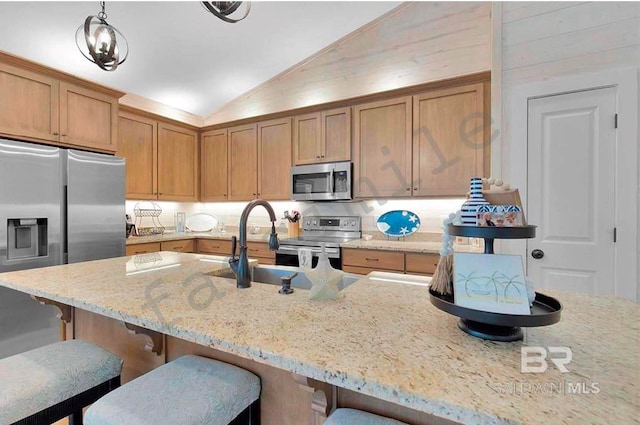 kitchen with light stone counters, a kitchen bar, lofted ceiling, hanging light fixtures, and stainless steel appliances