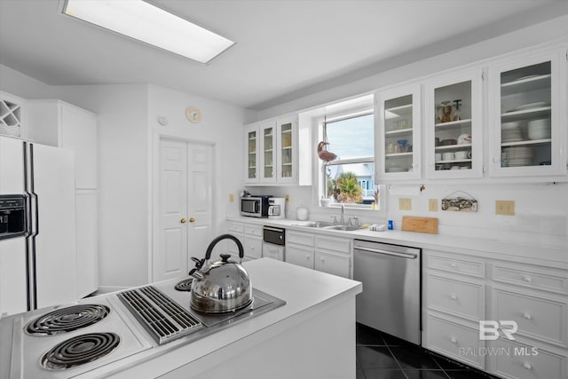 kitchen featuring stainless steel appliances, dark tile patterned flooring, sink, and white cabinets