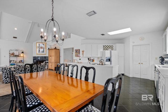 tiled dining area featuring an inviting chandelier, sink, and lofted ceiling with skylight