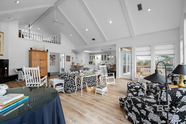 living room featuring ceiling fan with notable chandelier, beam ceiling, high vaulted ceiling, and light hardwood / wood-style flooring