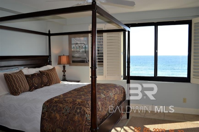 tiled bedroom featuring ceiling fan and a water view