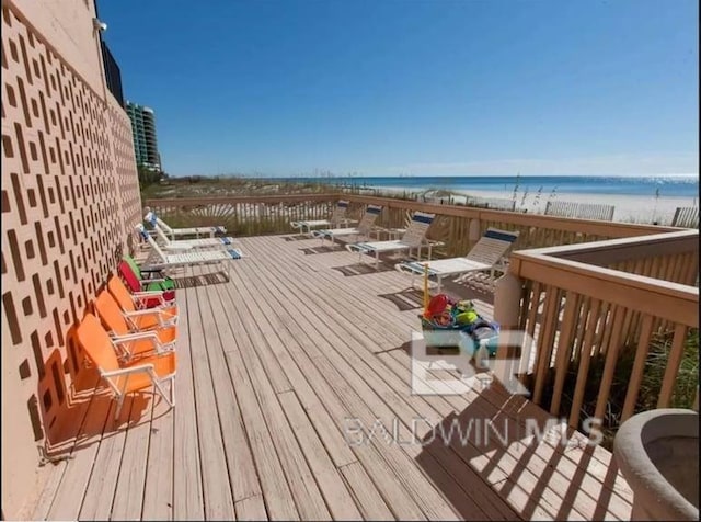 wooden terrace featuring a water view and a view of the beach