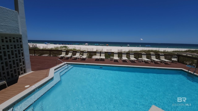 view of swimming pool featuring a water view and a beach view