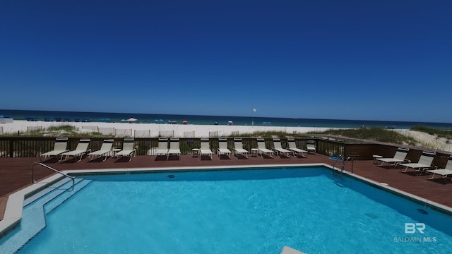 view of swimming pool featuring a water view and a view of the beach