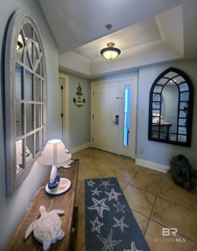 entryway featuring tile patterned flooring and a raised ceiling