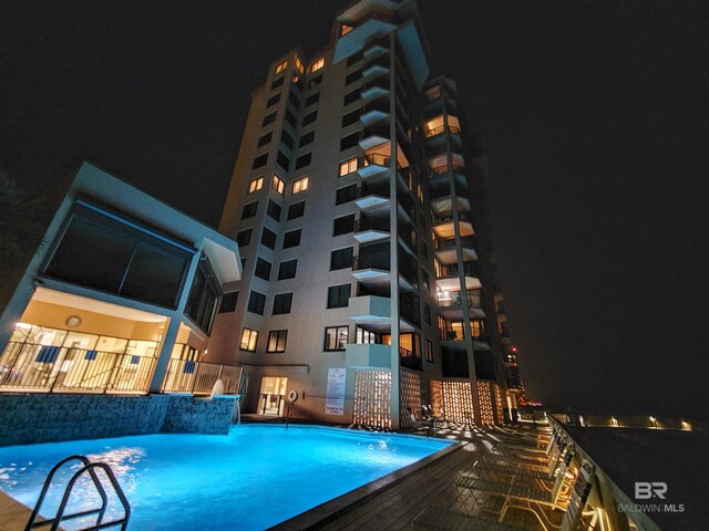 pool at night featuring pool water feature