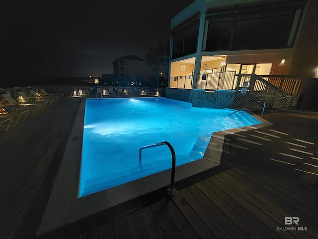 pool at night with a wooden deck