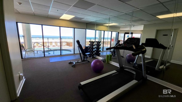 gym with a paneled ceiling and a water view