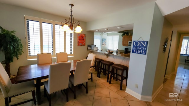 dining area featuring light tile patterned flooring and an inviting chandelier