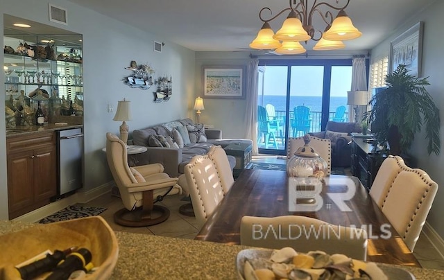 tiled dining space featuring a notable chandelier, a water view, and bar