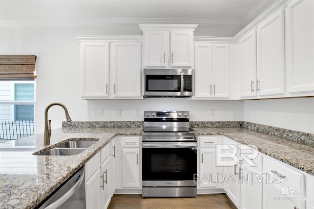 kitchen featuring appliances with stainless steel finishes, white cabinets, a sink, and ornamental molding