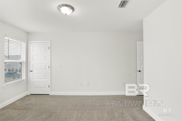 carpeted empty room featuring visible vents and baseboards