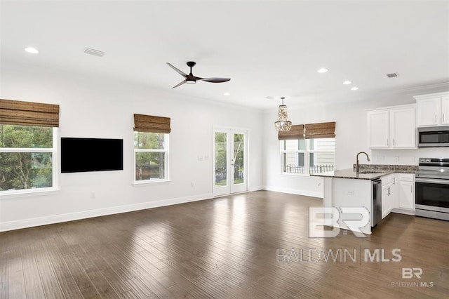 kitchen featuring a sink, white cabinetry, open floor plan, appliances with stainless steel finishes, and crown molding