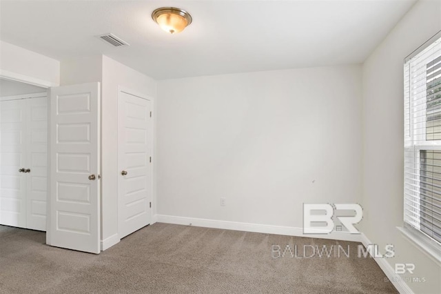 unfurnished bedroom featuring carpet floors, visible vents, and baseboards