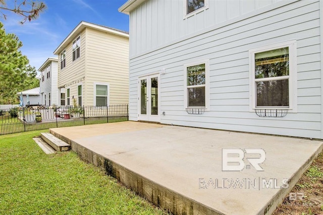 rear view of property with a yard, fence, board and batten siding, and a patio