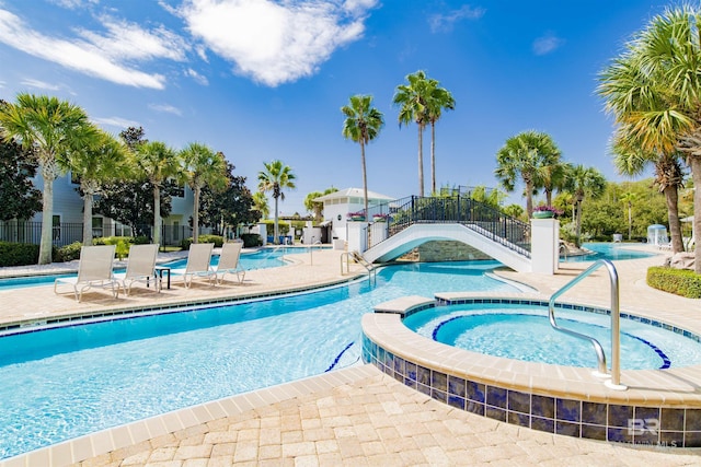 community pool featuring a community hot tub, a patio area, and fence