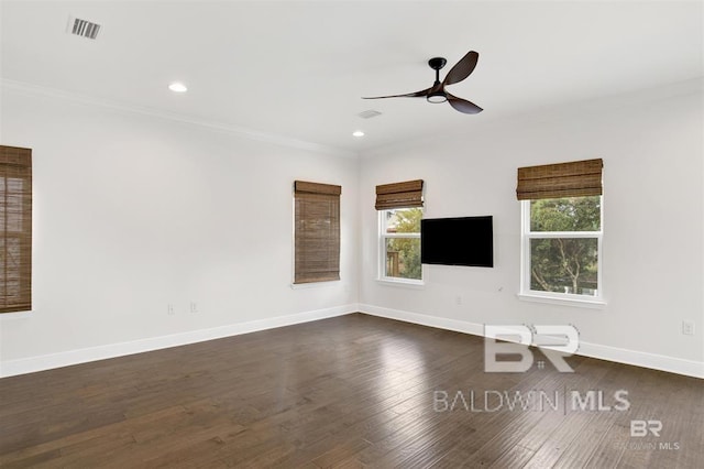 unfurnished room featuring dark wood-style floors, crown molding, visible vents, a ceiling fan, and baseboards