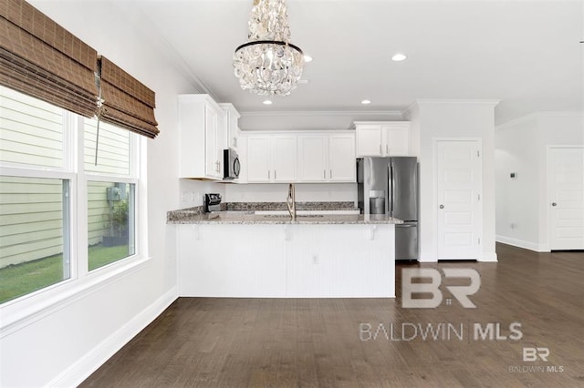 kitchen with white cabinets, a peninsula, light stone countertops, stainless steel appliances, and a sink