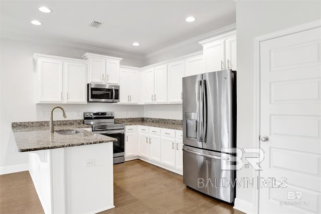 kitchen with visible vents, a peninsula, stainless steel appliances, white cabinetry, and a sink