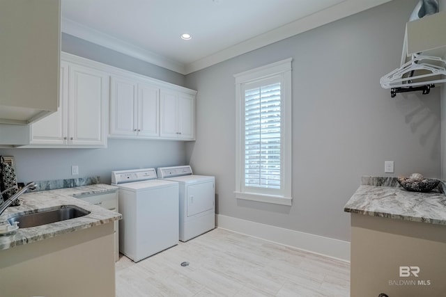 washroom with cabinets, ornamental molding, washer and clothes dryer, and sink