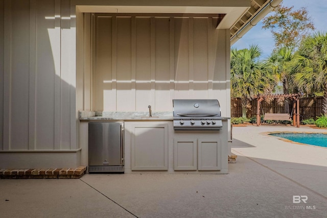 view of patio with area for grilling, a grill, a fenced in pool, and sink