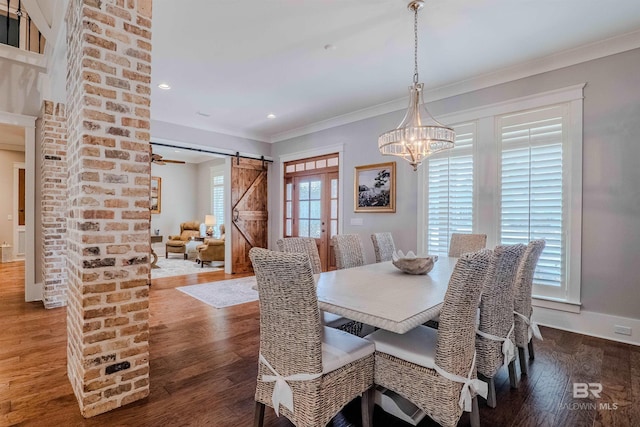 dining room with hardwood / wood-style flooring, ornamental molding, a barn door, and a notable chandelier