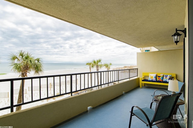 balcony featuring a view of the beach and a water view