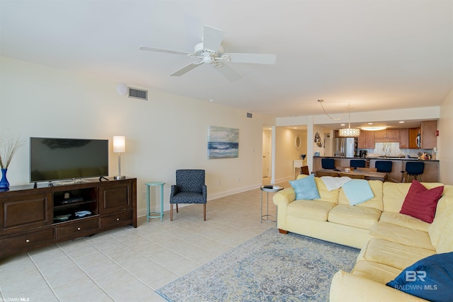 living room featuring light tile patterned floors, a ceiling fan, visible vents, and baseboards