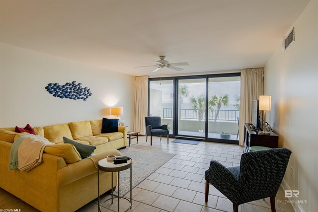 tiled living room featuring expansive windows and ceiling fan