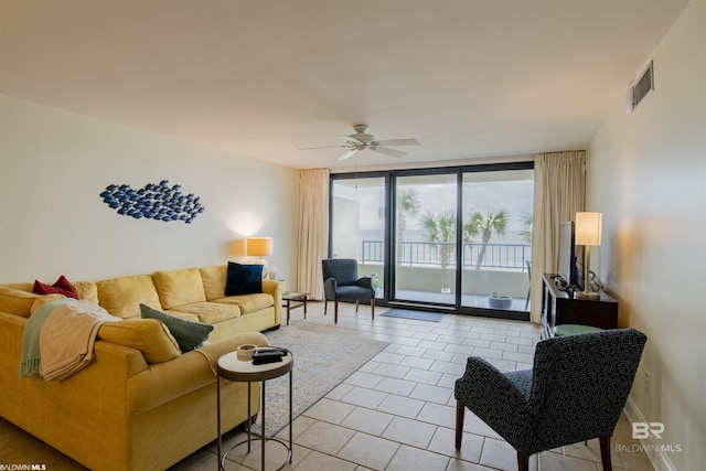 living area featuring light tile patterned floors, expansive windows, visible vents, and ceiling fan