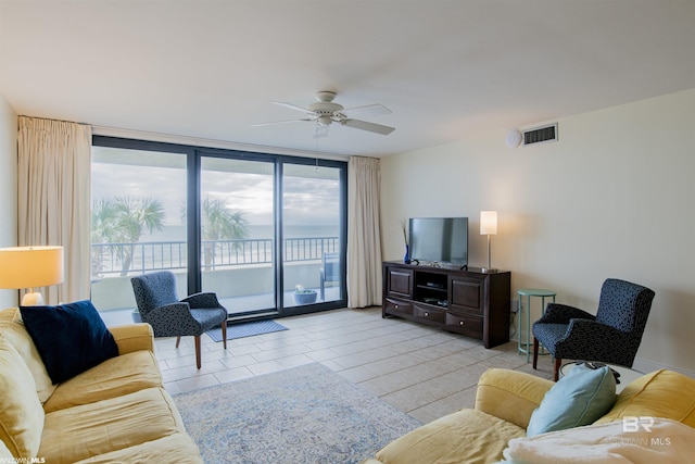 living room featuring a ceiling fan, visible vents, and expansive windows