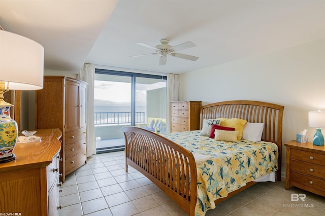 bedroom featuring a water view, a wall of windows, access to outside, light tile patterned floors, and ceiling fan