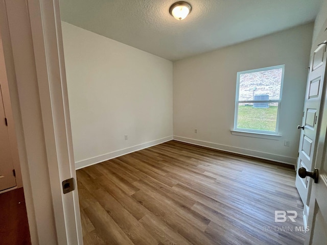 empty room with a textured ceiling and light wood-type flooring