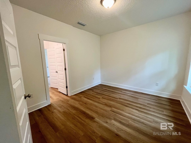 unfurnished bedroom featuring dark hardwood / wood-style flooring and a textured ceiling