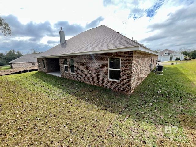 rear view of property featuring a patio, central air condition unit, and a lawn