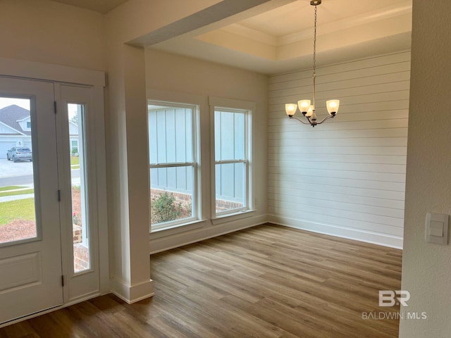 foyer with a tray ceiling, hardwood / wood-style flooring, and a notable chandelier