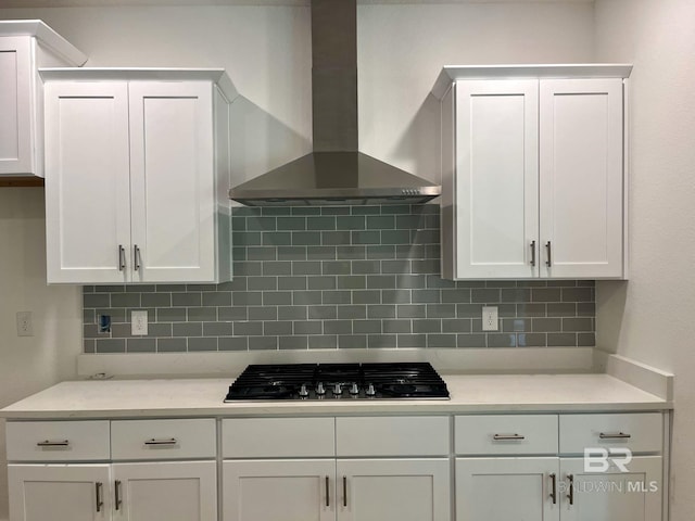 kitchen featuring backsplash, white cabinetry, wall chimney exhaust hood, and gas stovetop