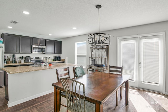 dining room featuring a textured ceiling, dark wood-type flooring, an inviting chandelier, and sink