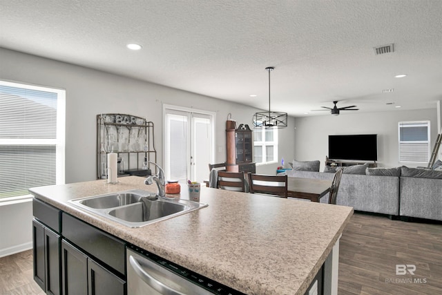 kitchen featuring dark wood-type flooring, sink, ceiling fan with notable chandelier, and a kitchen island with sink