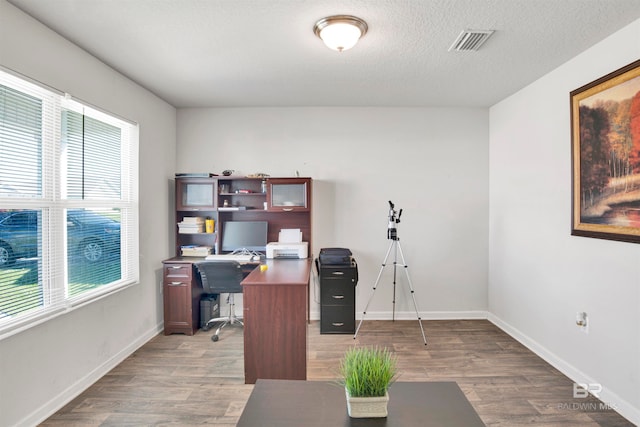 office space featuring a textured ceiling, a healthy amount of sunlight, and dark wood-type flooring