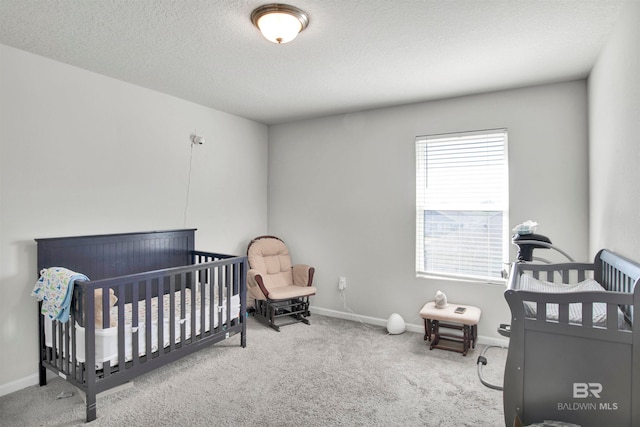 bedroom with a textured ceiling, carpet, and a nursery area