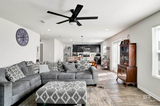 living room with a textured ceiling, ceiling fan, and wood-type flooring