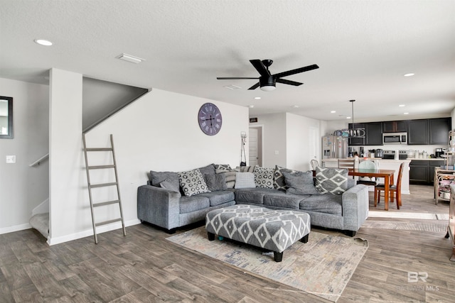 living room with hardwood / wood-style floors, ceiling fan, and a textured ceiling