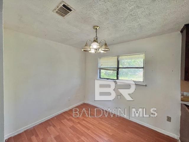 208 Lee St, Atmore, AL 36502 - empty room featuring wood finished floors, a textured ceiling, a chandelier, baseboards, and visible vents