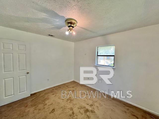208 Lee St, Atmore, AL 36502 - carpeted spare room with a textured ceiling, visible vents, baseboards, and ceiling fan