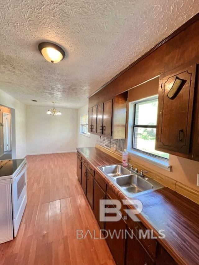 208 Lee St, Atmore, AL 36502 - kitchen featuring light wood-style flooring, a sink, a textured ceiling, white electric range, and a notable chandelier