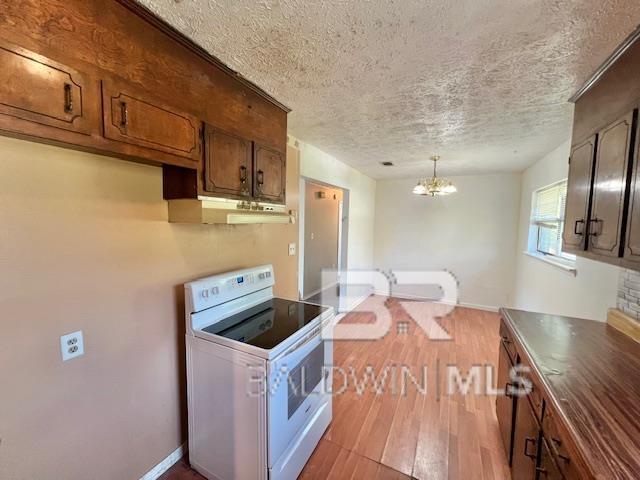 208 Lee St, Atmore, AL 36502 - kitchen featuring a textured ceiling, electric range, a chandelier, wood finished floors, and under cabinet range hood