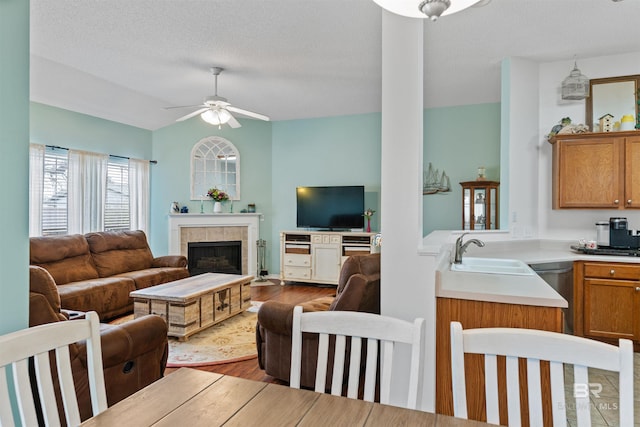 living room featuring a fireplace, lofted ceiling, ceiling fan, a textured ceiling, and wood finished floors